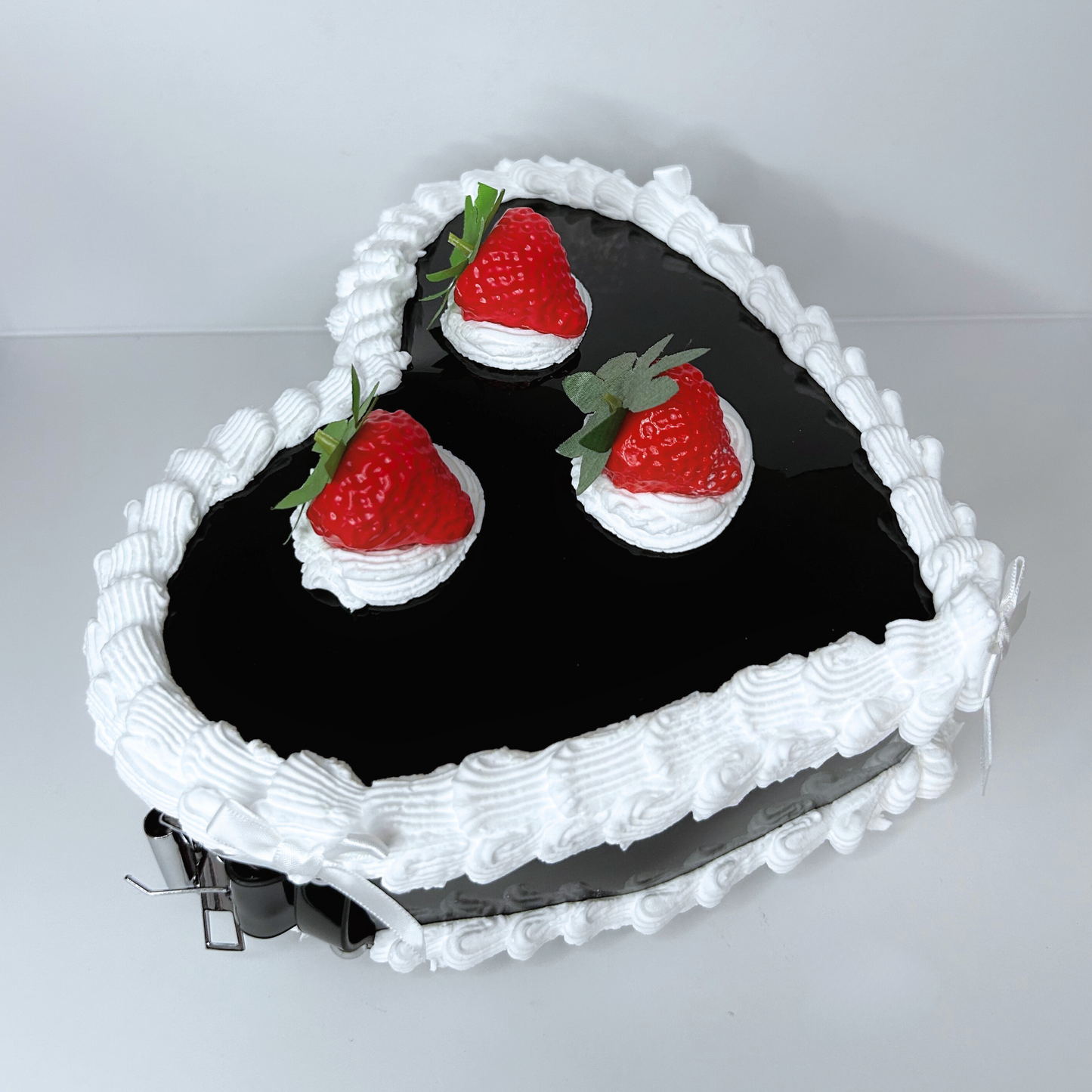 Side view of the black heart-shaped purse with white coquette bows and textured frosting.