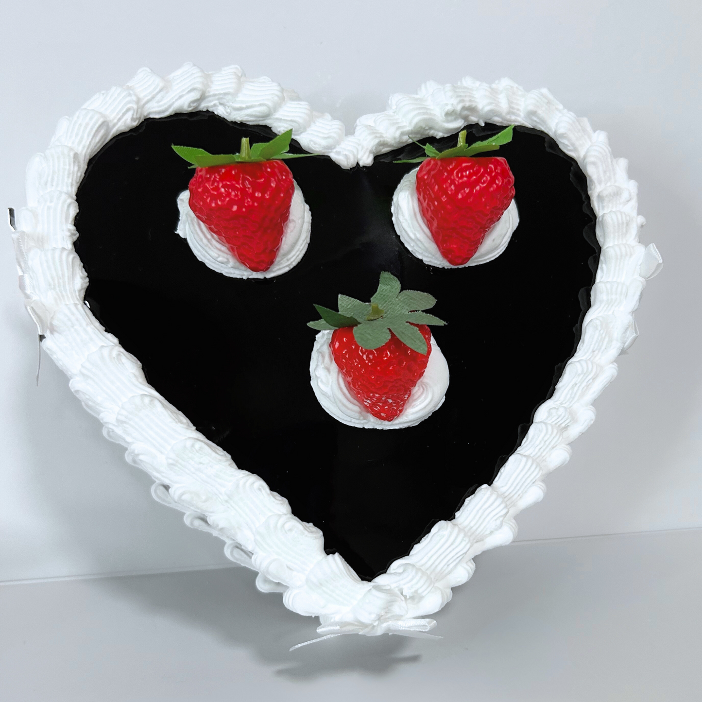 Bottom angle of the black strawberry cake purse highlighting durable construction and heart silhouette.