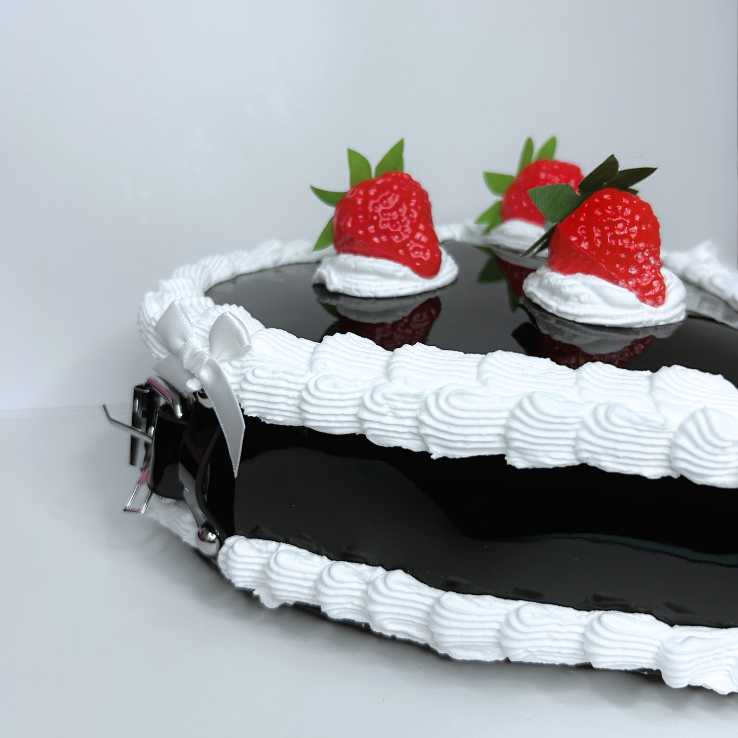 Close-up of the black strawberry cake purse showing intricate frosting and bow accents.