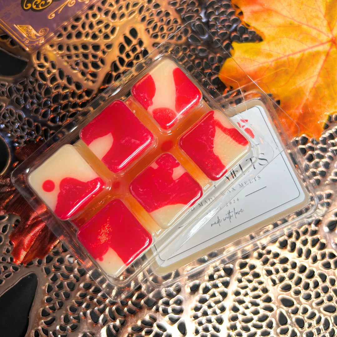 Packaged wax melts with red and white design on a decorative surface with leaves.