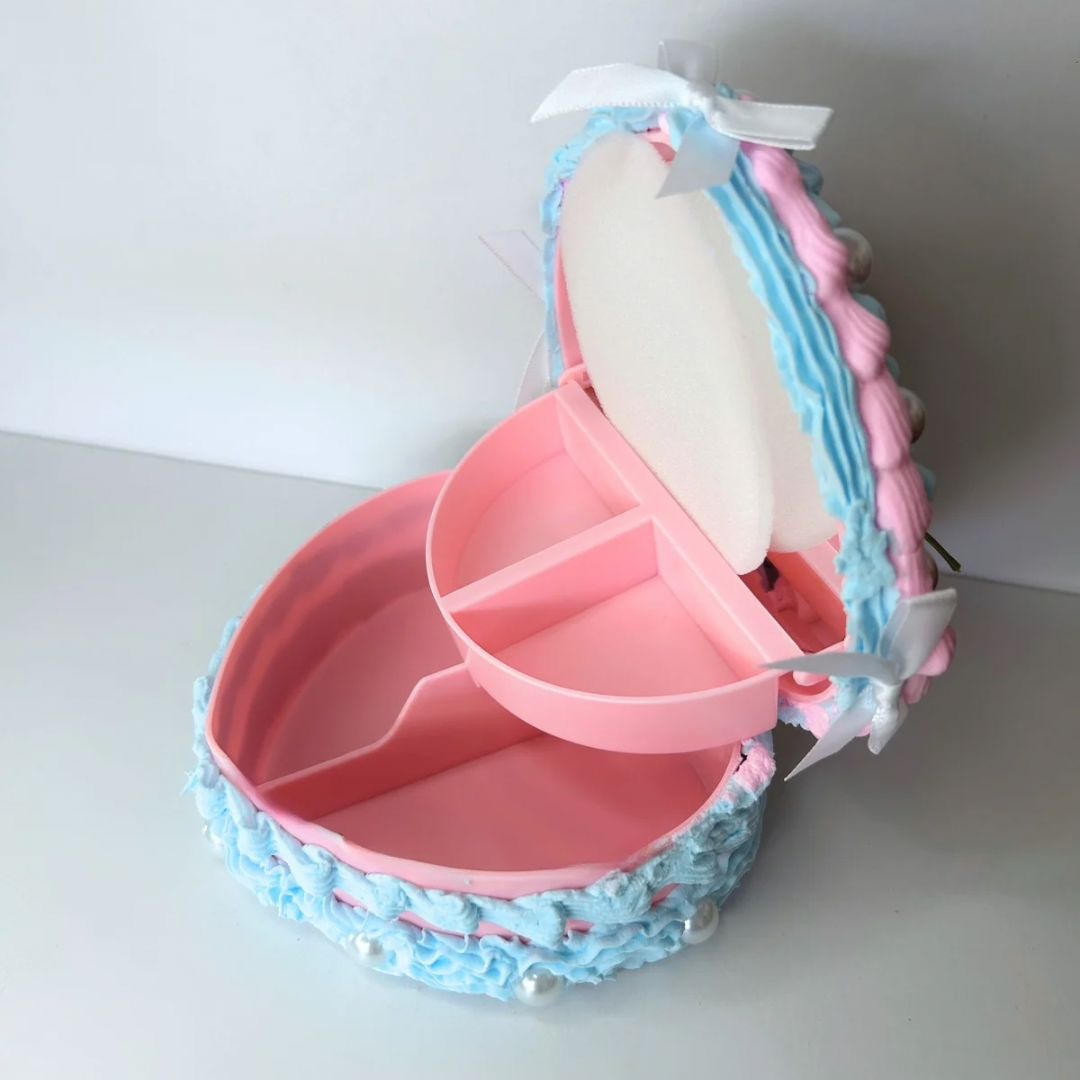 Angled open view of the Blue Vintage Heart-Shaped Jewelry Box, featuring its interior space for jewelry storage, soft blue exterior, and decorative accents of pearls and white bows.