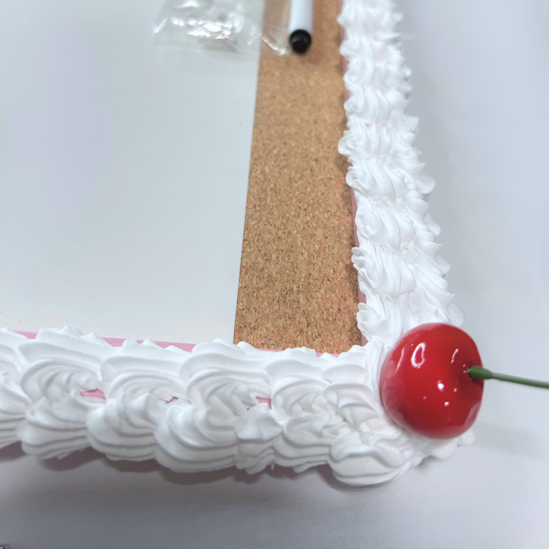 Detailed corner view of cherry frosted whiteboard showing pink frame and frosting.