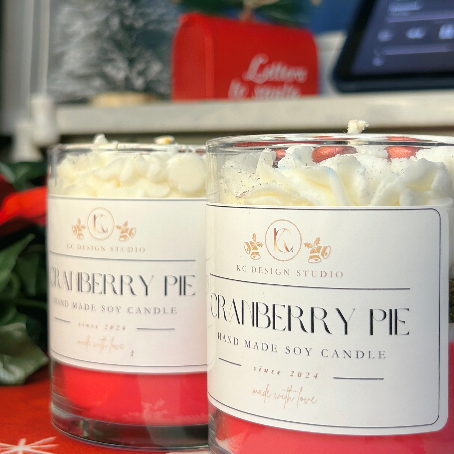 Close-up of two cranberry pie candles with layers of crumbs and cream, topped with Christmas-shaped cranberry decorations.