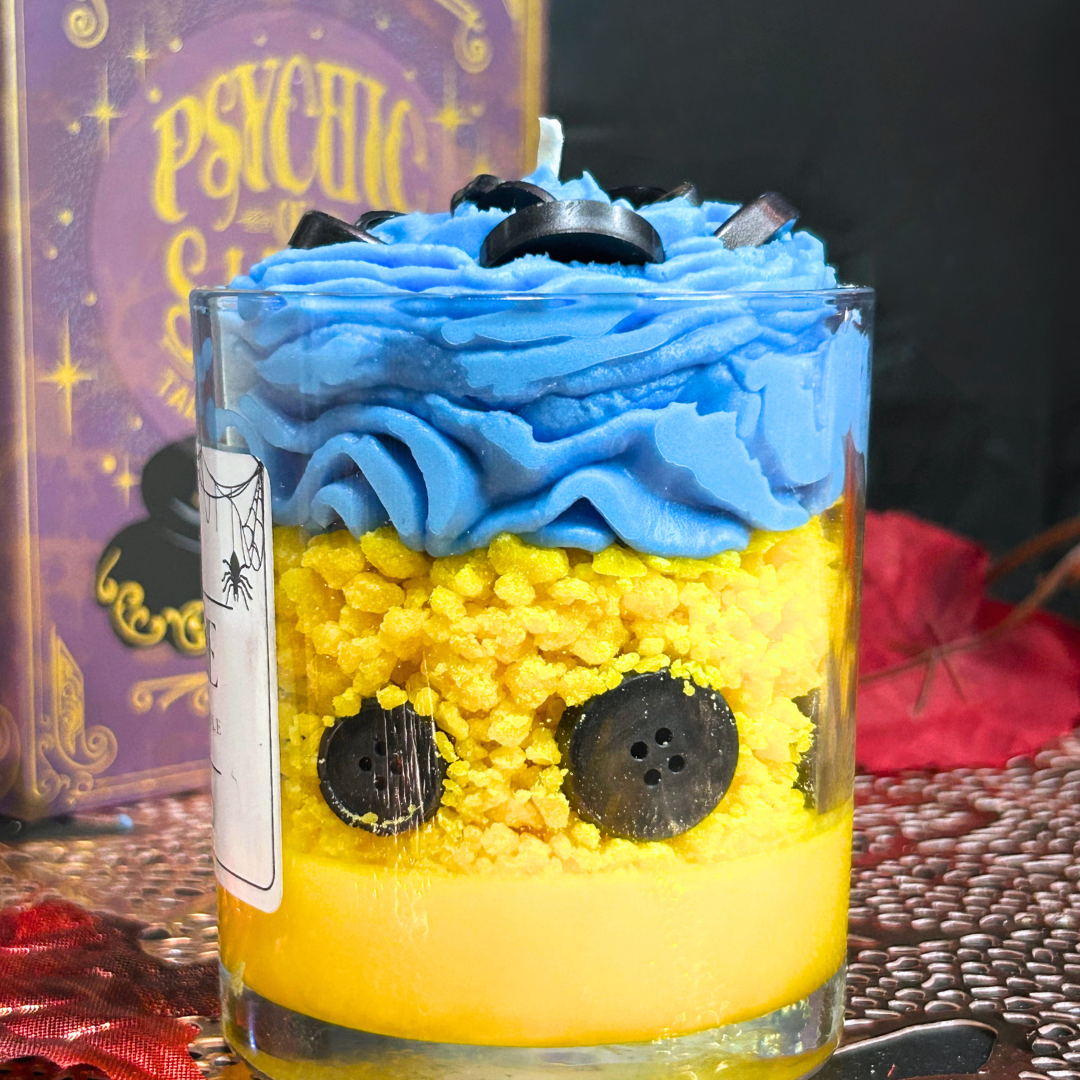 Side view of Coraline Candle with buttons lined around the vessel and blue whipped cream swirl on top