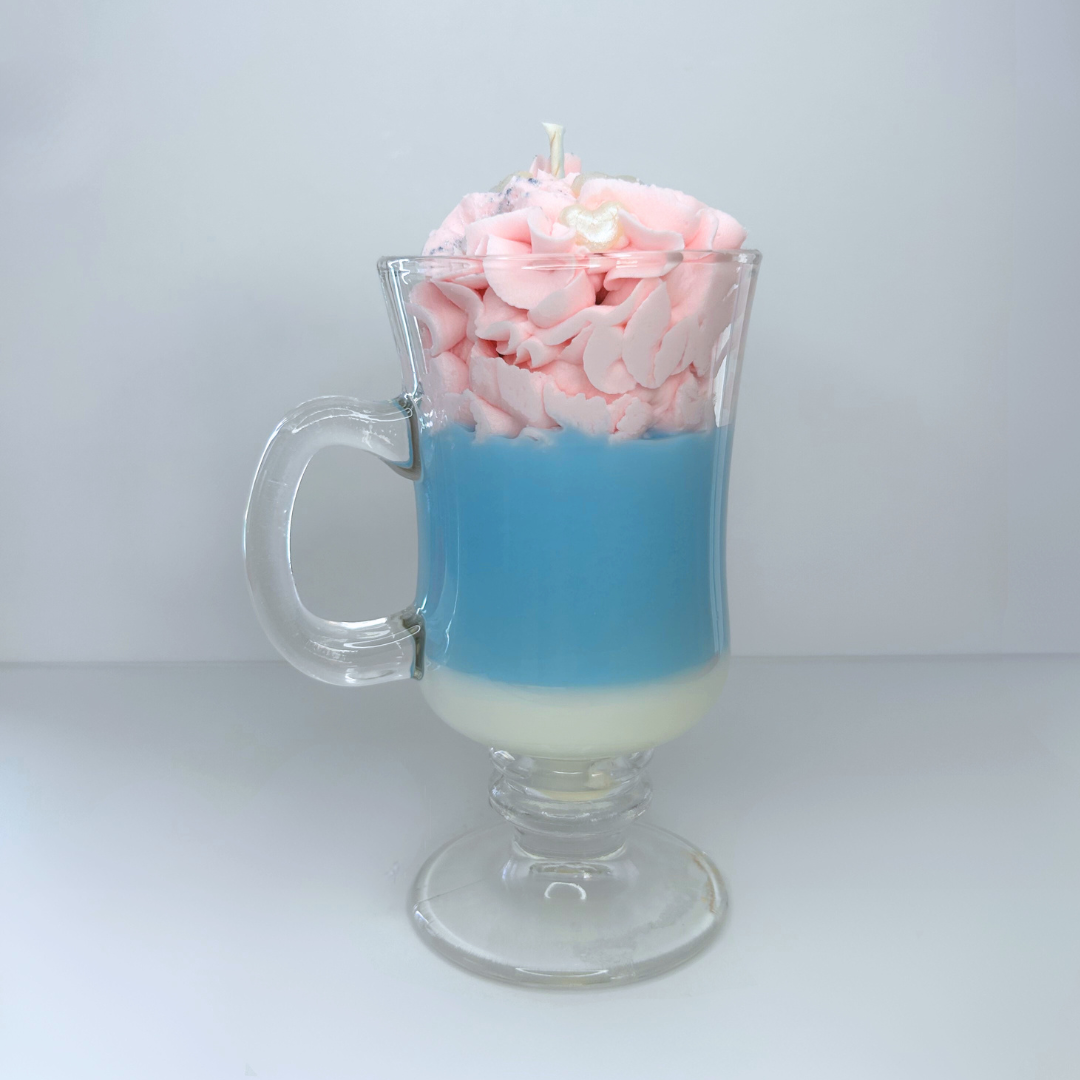 Front view of cotton candy-inspired candle in clear mug with pink whipped topping and heart sprinkles.