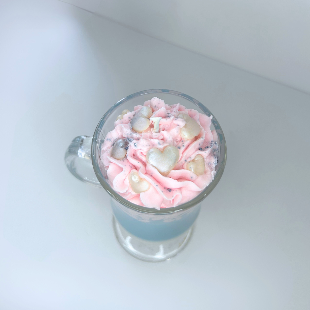 Top view of cotton candy candle showing pink whipped topping, heart sprinkles, and blue powder detail.