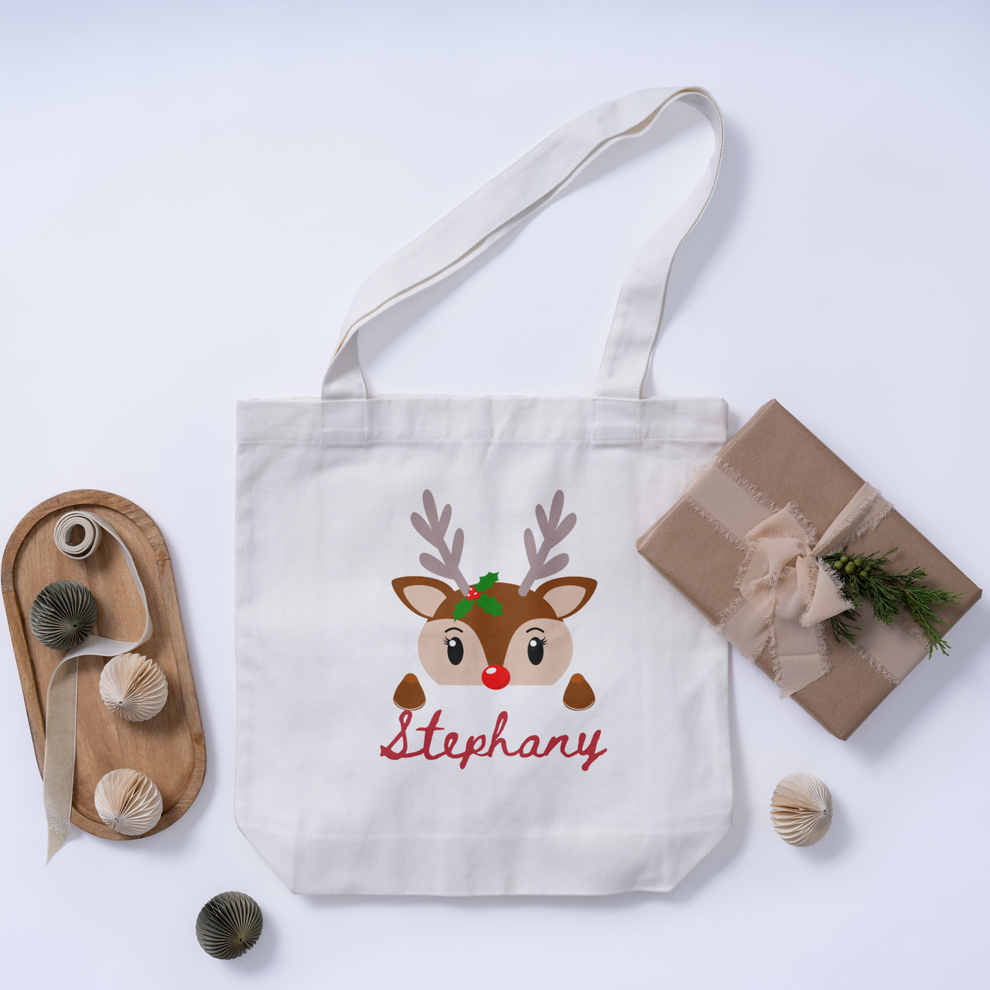 Top view of a custom Christmas white tote bag with a reindeer design on the initial and an option for a personalized name for a unique holiday gift.