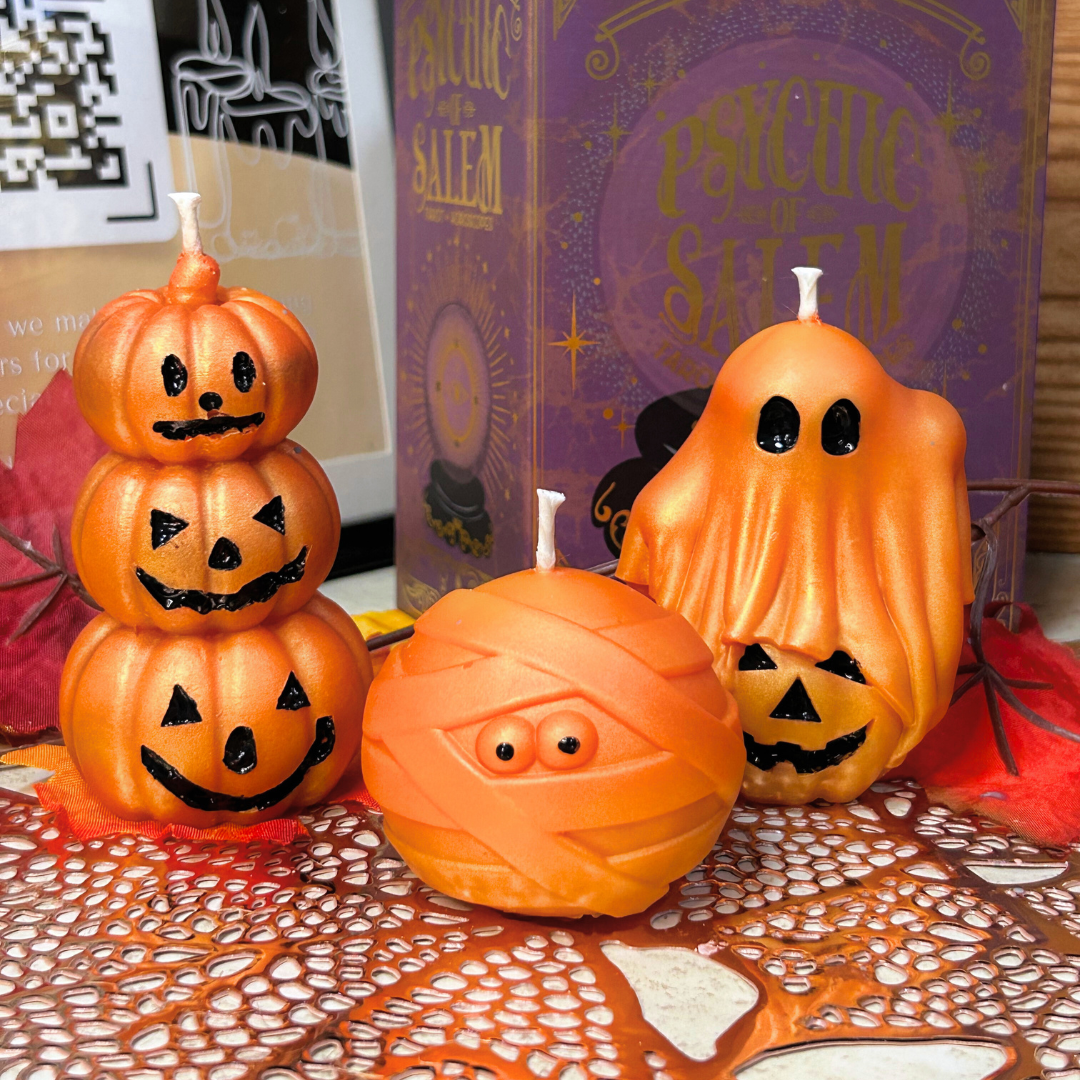 Halloween-themed candles including a stack of pumpkin-shaped candles, a mummy-shaped candle, and a ghost-shaped candle.
