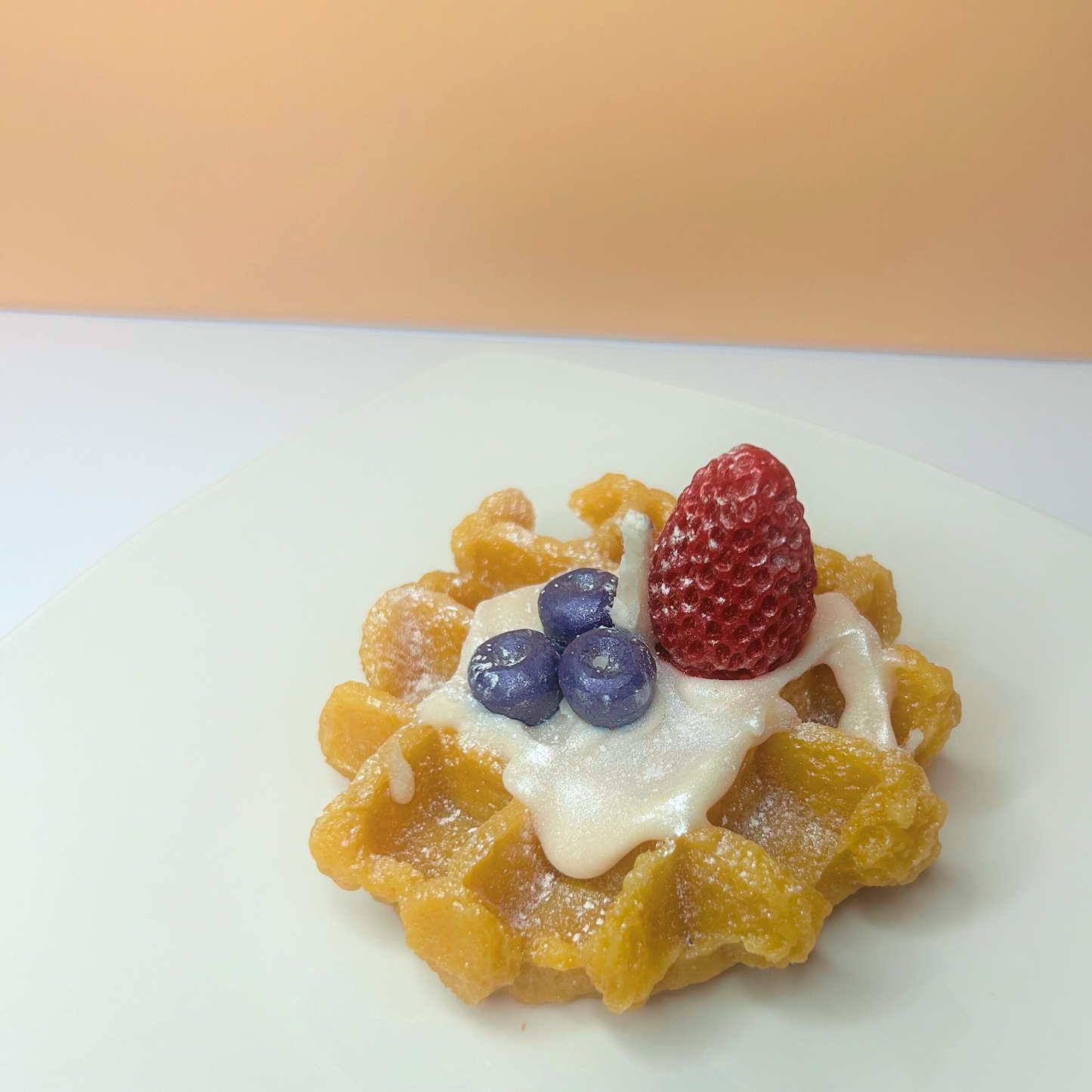 Front view of decorative French Waffle Scented Candle featuring a charming design and a blend of caramel, vanilla, blueberry, and strawberry scents.