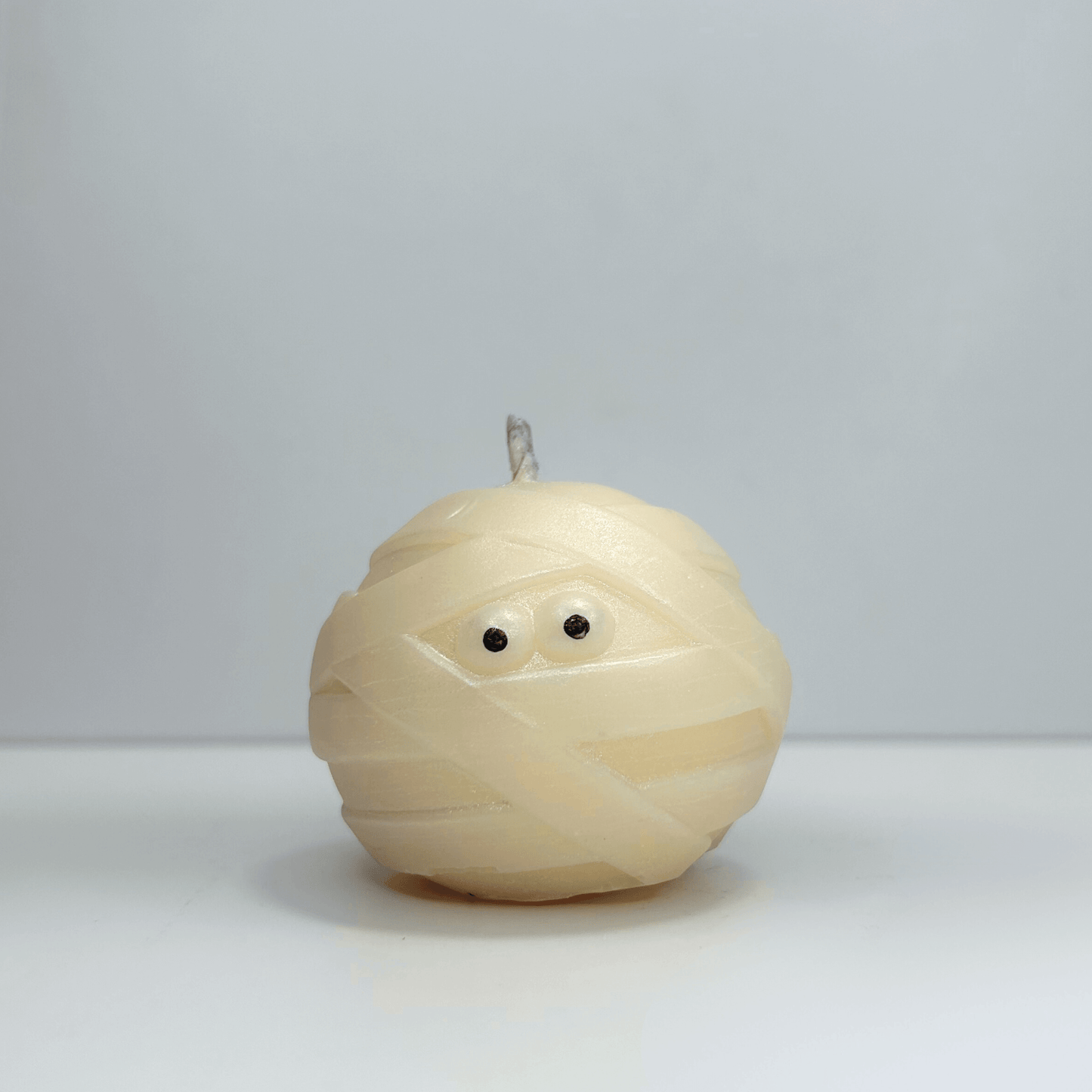Front view of decorative mummy candle with visible eyes, perfect for Halloween decor.