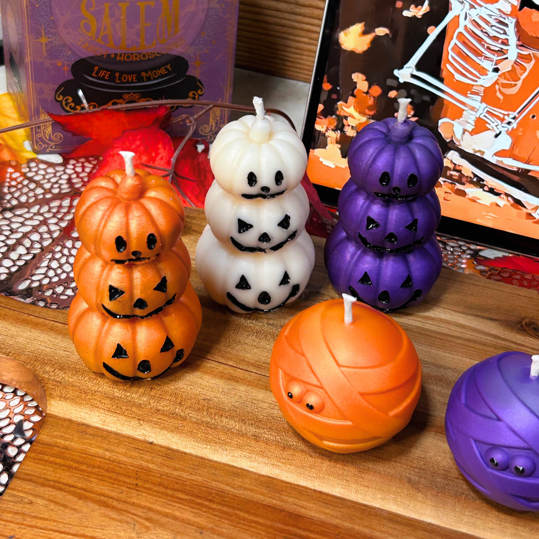 Halloween-themed candles on a wooden surface with decorative items in the background.