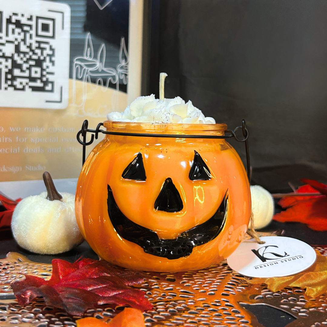 Halloween-themed candle in a jack-o'-lantern design with decorative elements on a table.