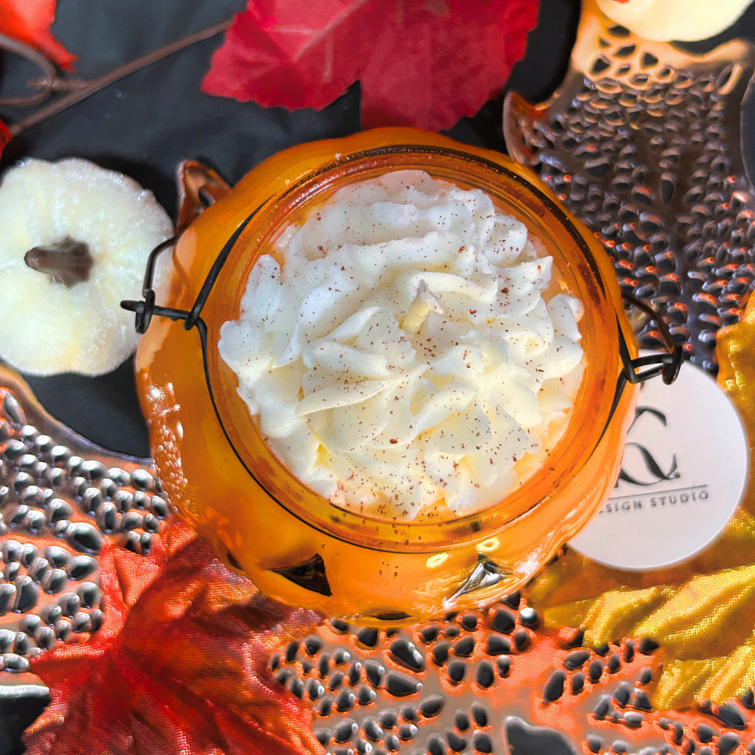 Orange lantern with white cream candle inside on a decorative surface with pumpkins and leaves.