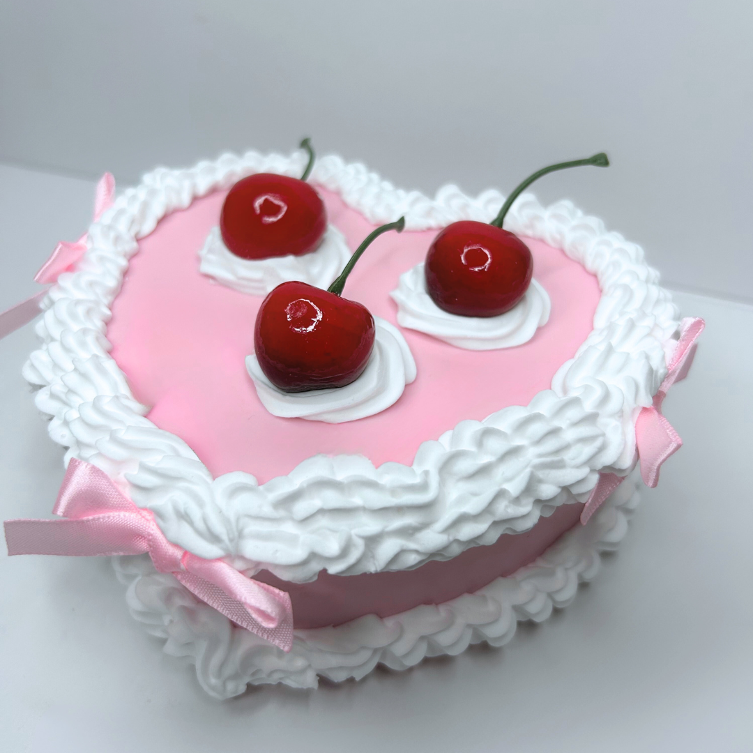 Close-up of the frosting texture, pink bows, and red cherries on the vintage cake jewelry box.