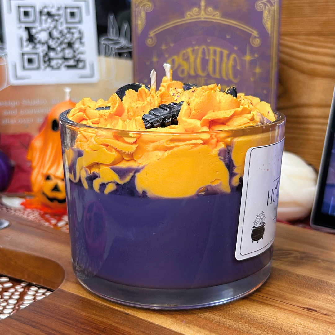 Halloween-themed candle with purple base and orange top on a wooden surface.