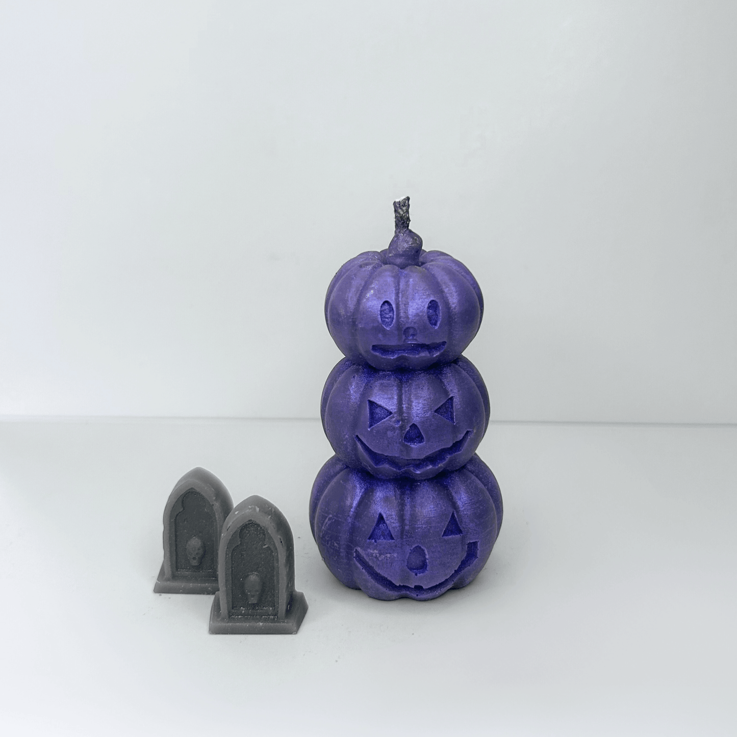 Front view of the purple Jack-O-Lantern Candle showcasing three stacked pumpkins with whimsical Halloween faces, adding a sparkly touch to Halloween celebrations.