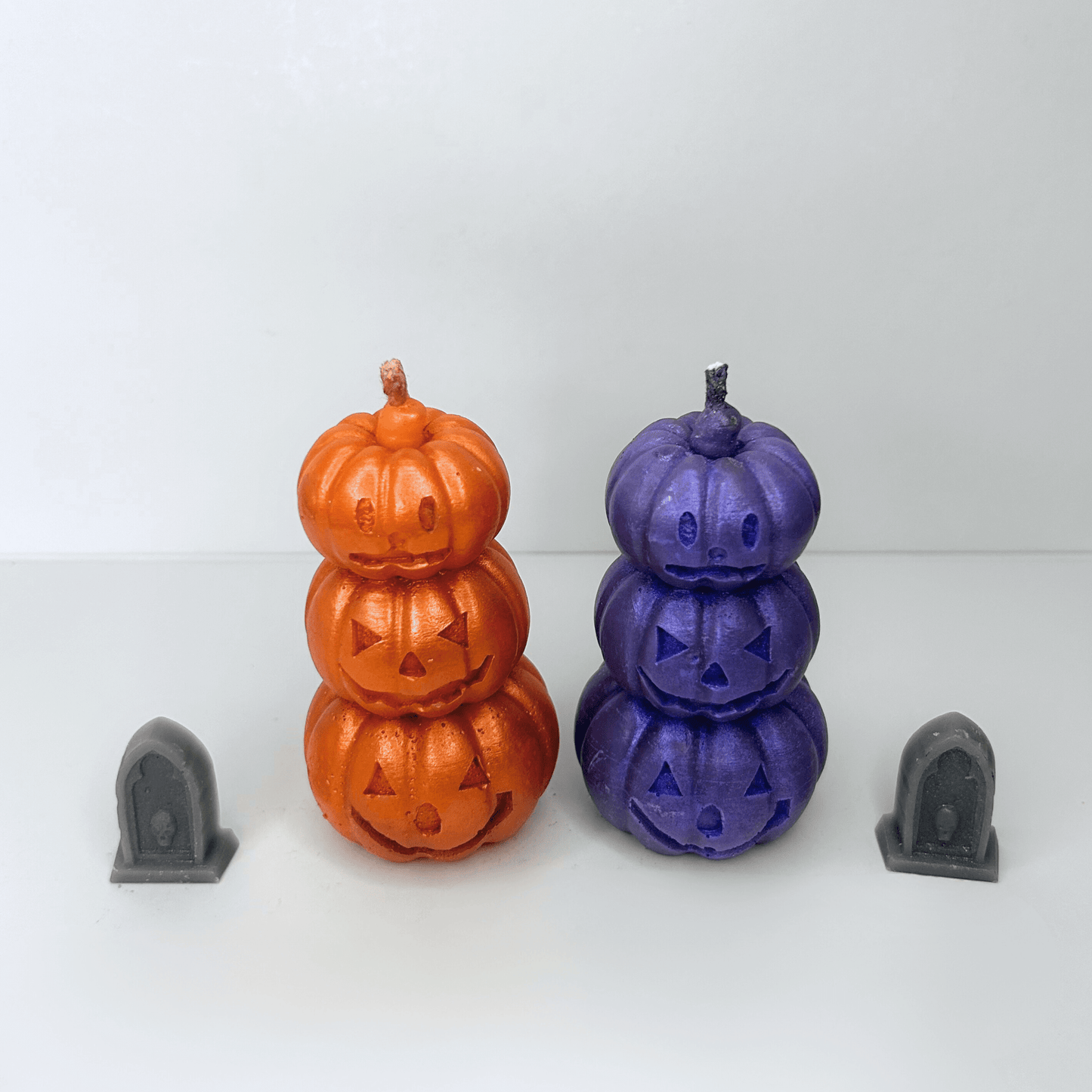 Top view of both the orange and purple Jack-O-Lantern Candles, highlighting their decorative carved pumpkin faces and sparkly finishes.