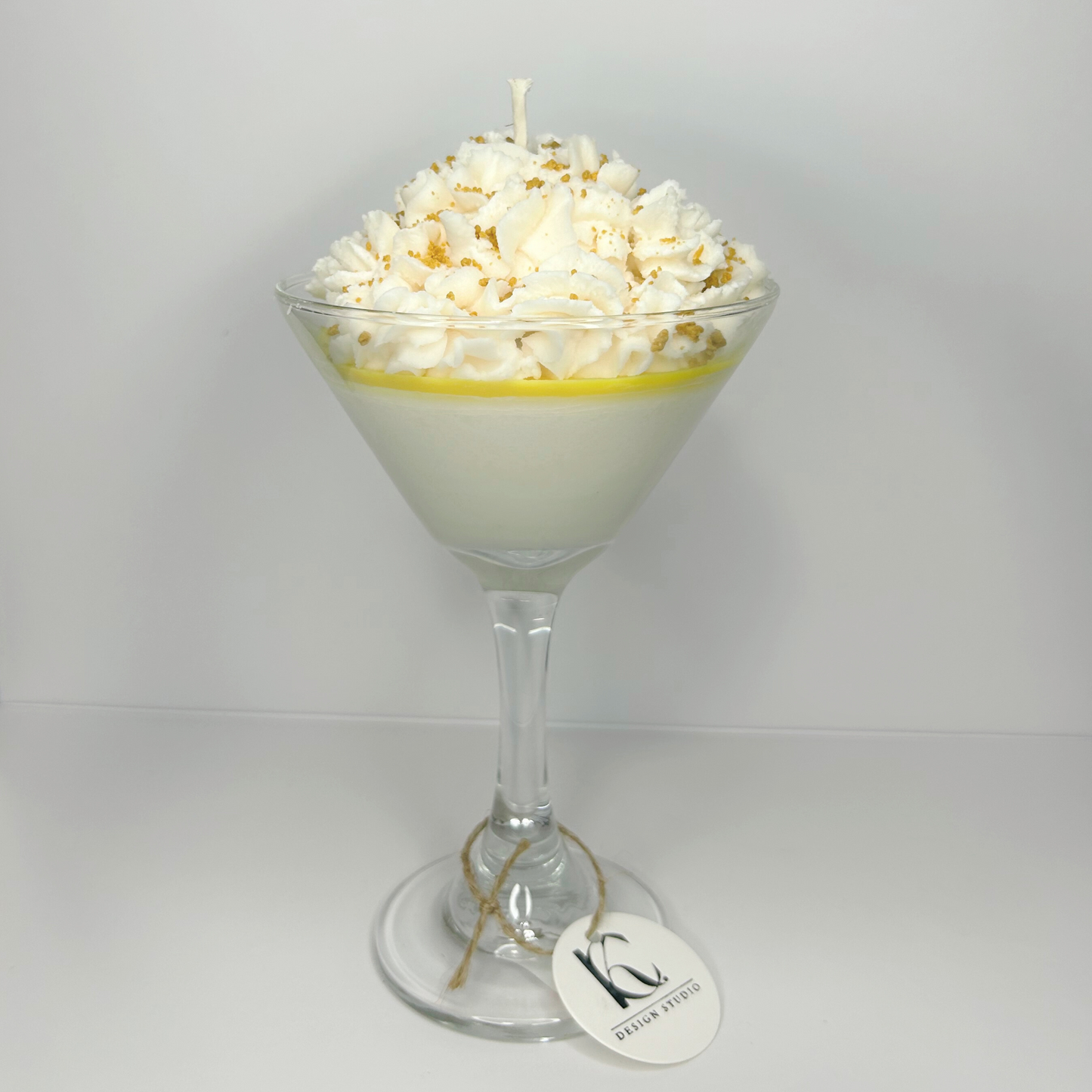 Angled view of Lemon Meringue Martini Candle with the soft glow of candlelight, showcasing its elegant presentation in a martini glass and the luxurious blend of vanilla, lemon, and caramel scents.