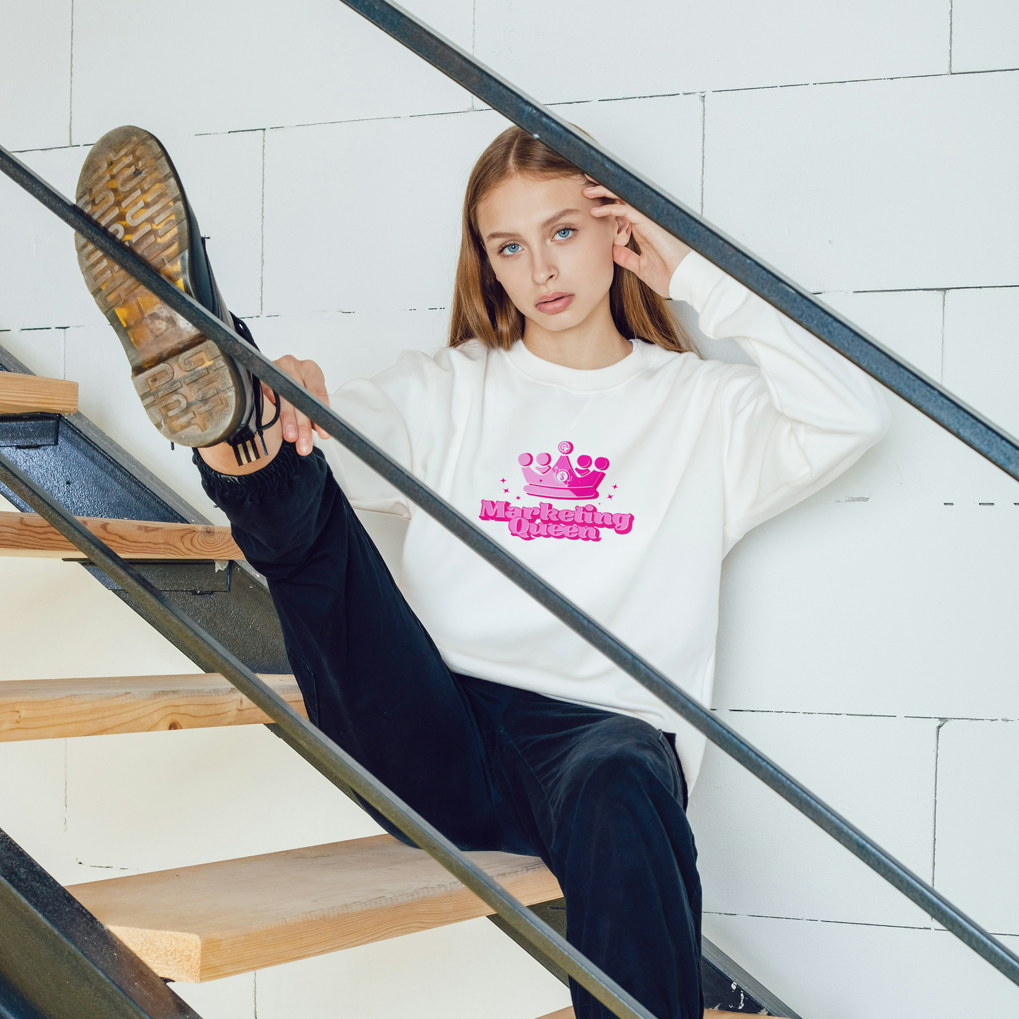 Marketing Queen long sleeve t-shirt in white on a woman sitting on a staircase – bold pink graphic, comfy fit, part of the Marketing Girly Collection.