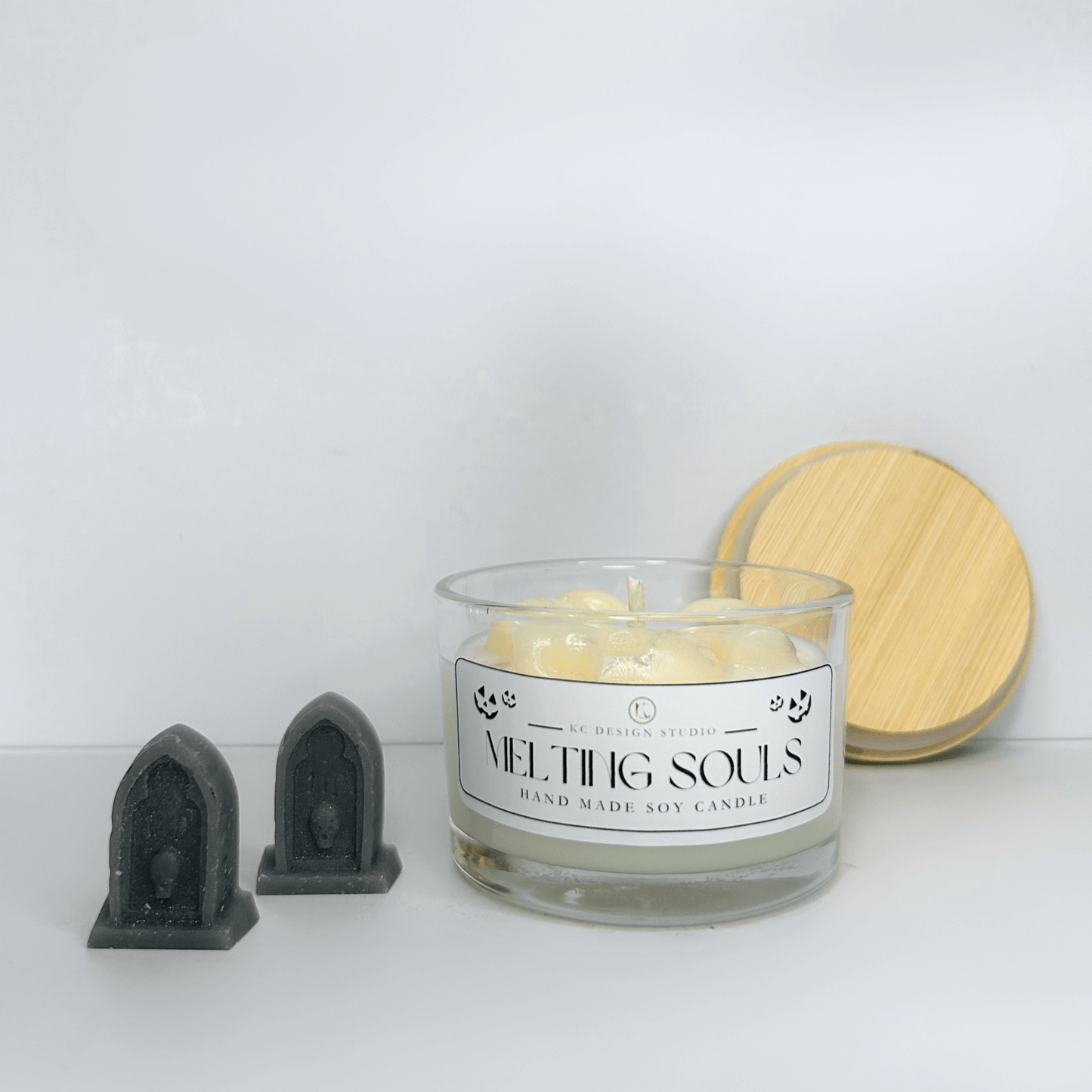 Front view of the Melting Souls Candle featuring three melting skulls and spooky Halloween decor.