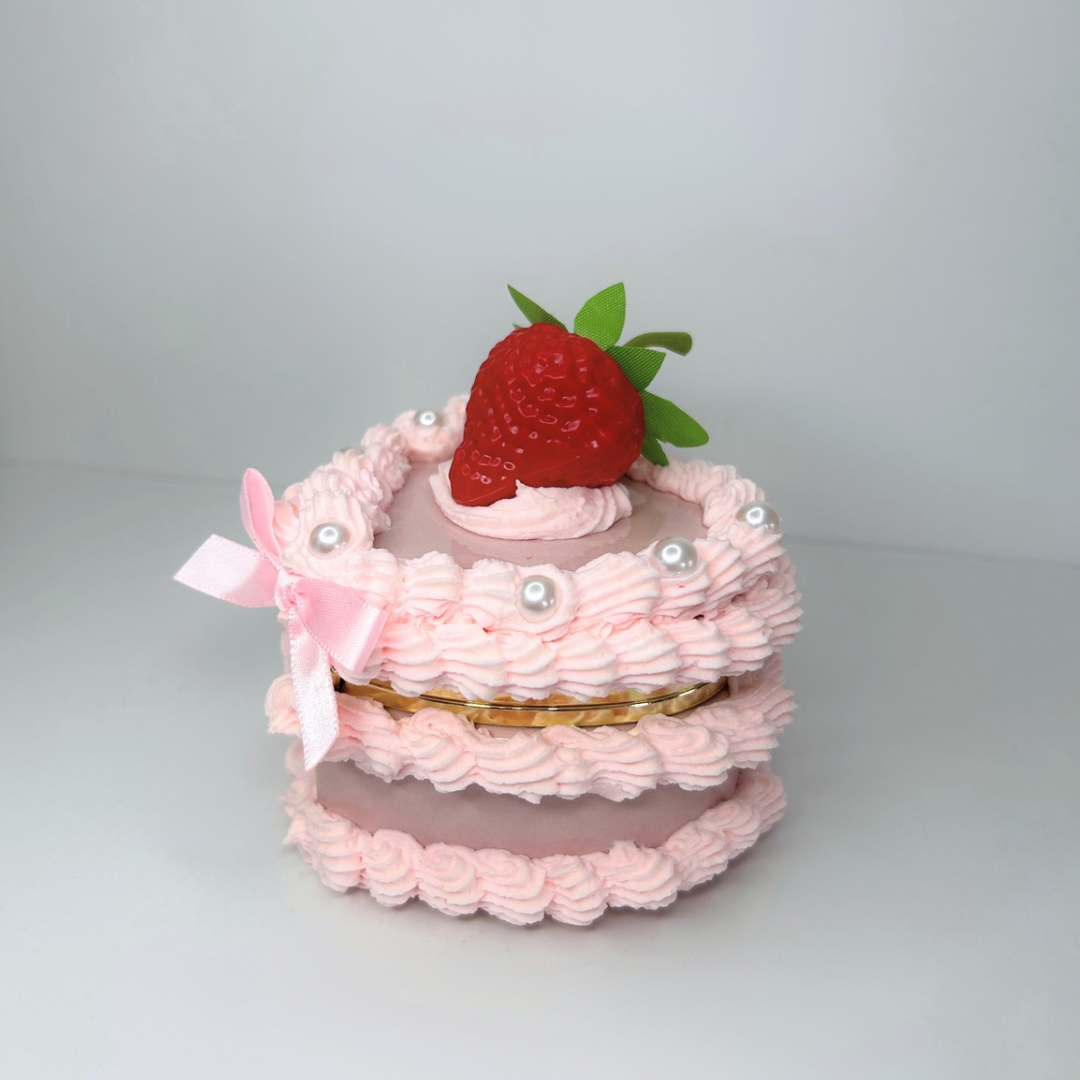 Side view of the Mini Strawberry Cake Jewelry Box, featuring a heart-shaped design, soft pink bow, shiny pearls, and a realistic strawberry on top.