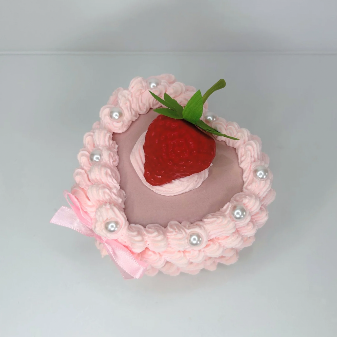 Top view of the Mini Strawberry Cake Jewelry Box, showcasing its adorable cake-like design with a pink bow, glossy pearls, and a sweet strawberry centerpiece.