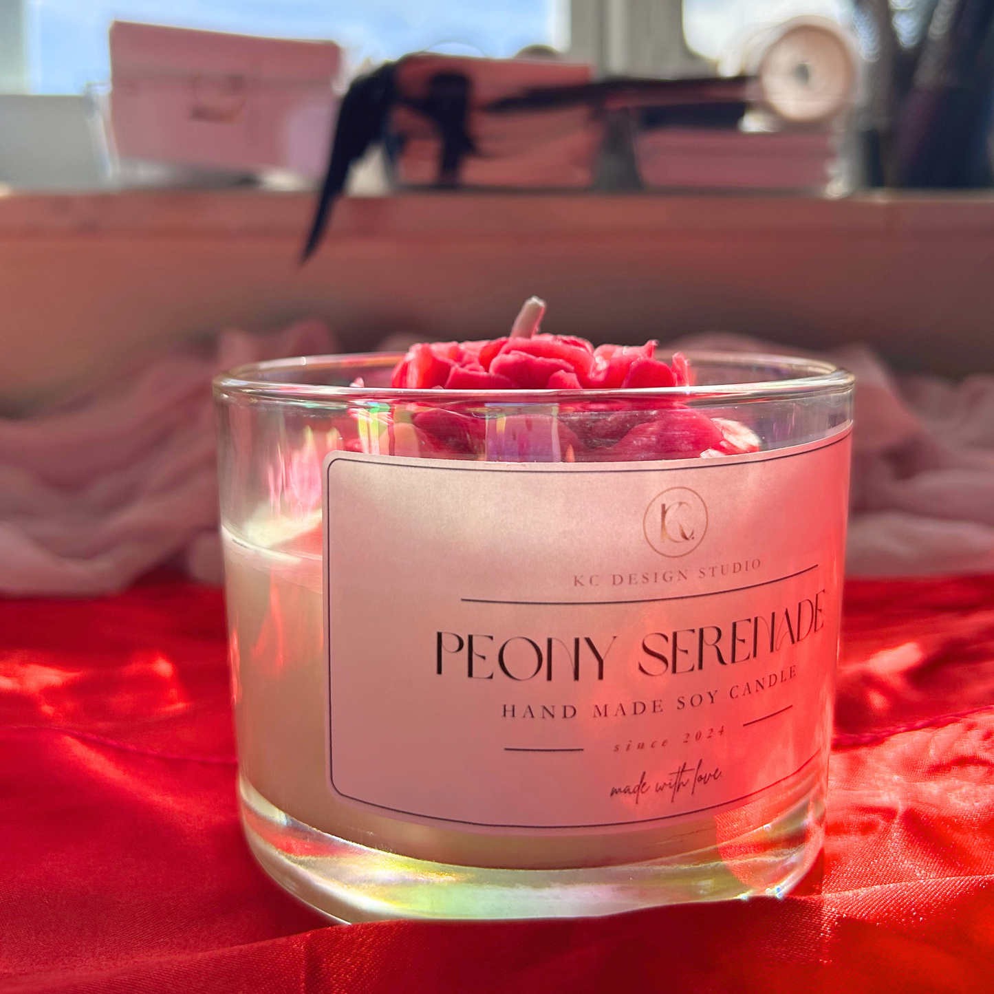 Side view of Peony Serenade candle, showcasing its luxurious peony and peach magnolia scent with a large decorative peony on top.