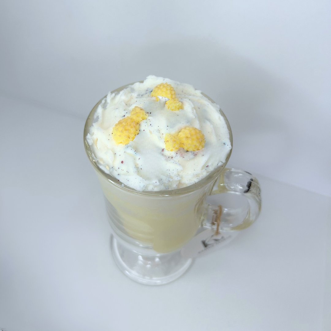 Angled shot of Piña Colada candle in clear Irish coffee mug with bright yellow base and pineapple decorations