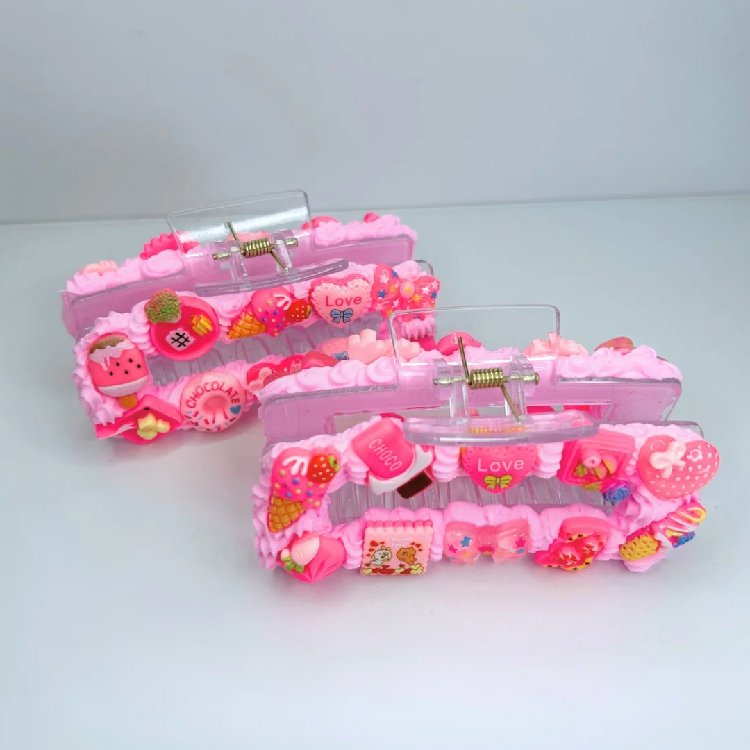 Pink creamy hair claws with geometric design and charms - angled view.