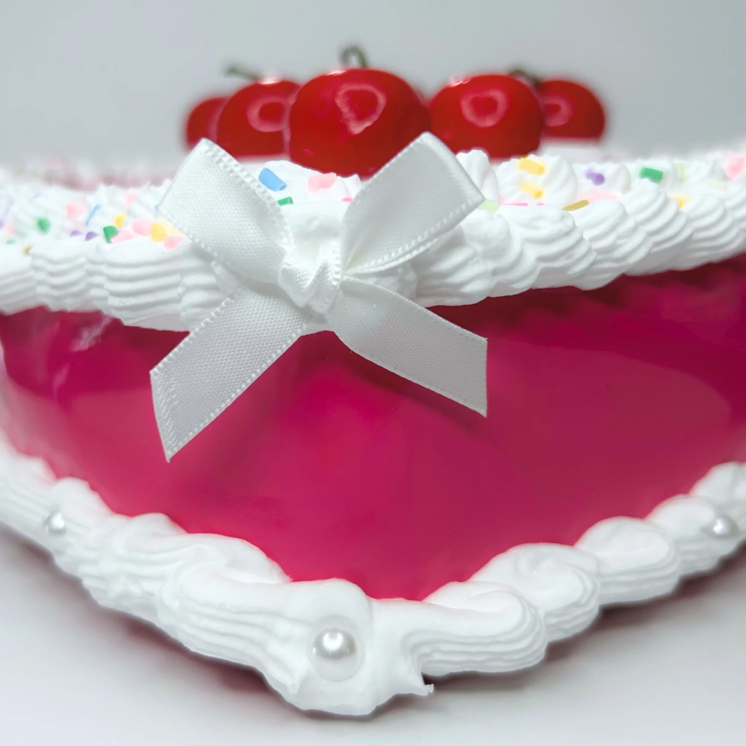 Close-up of cherry cake purse details including textured frosting, pastel pink base, and realistic cherry design