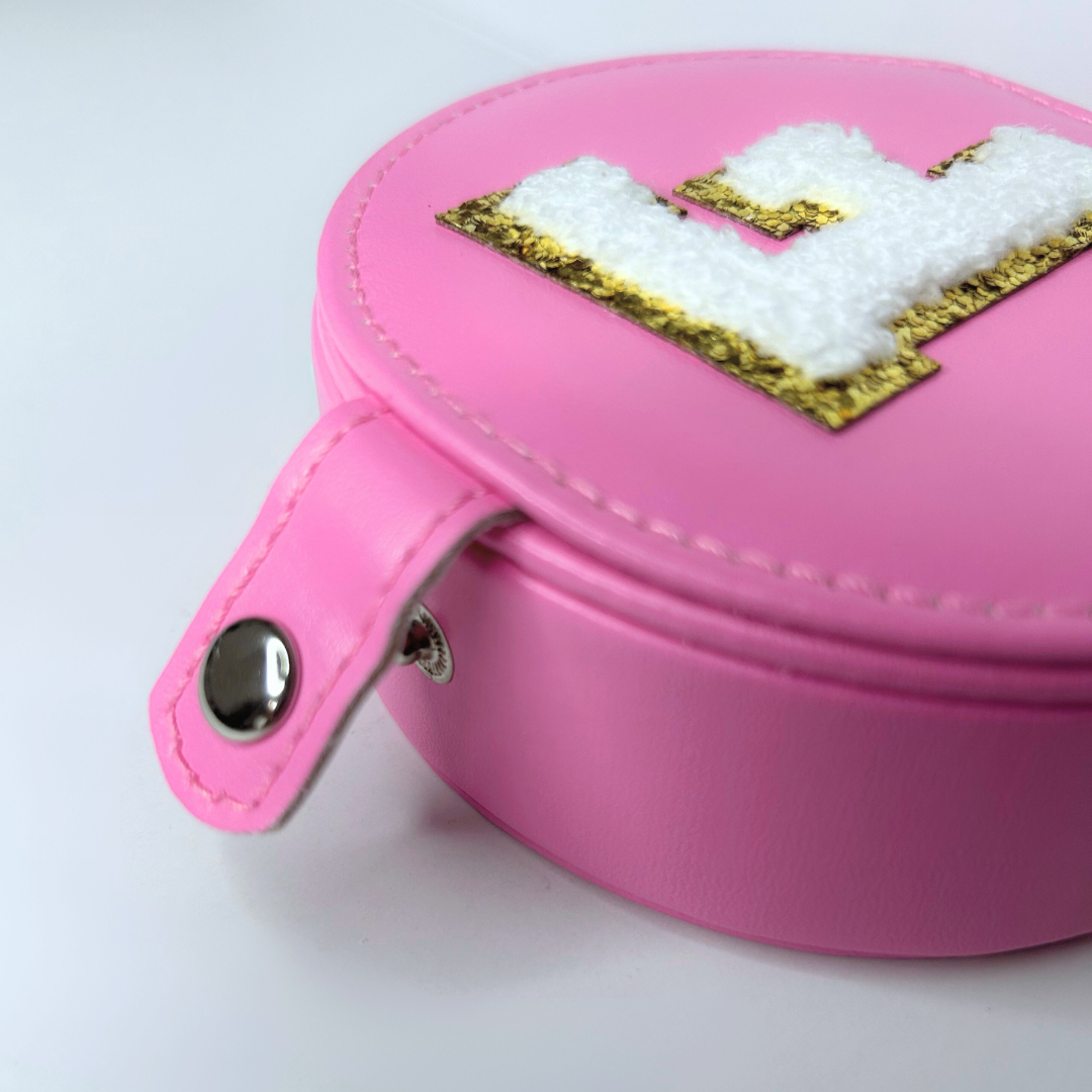 Close-up of button closure on pink jewelry travel case with initial.