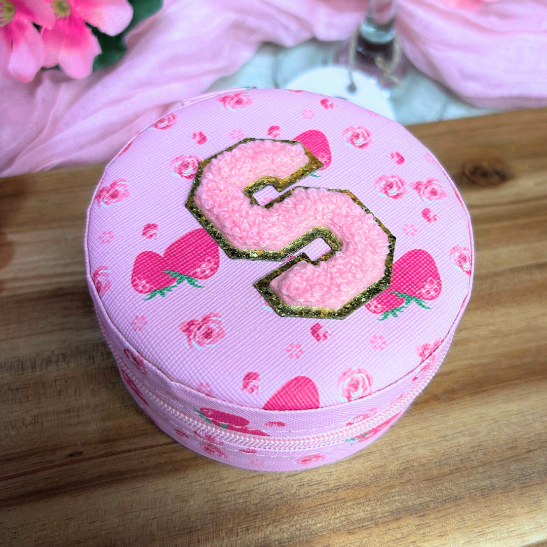 Side view of a pink personalized jewelry travel case for Valentine’s Day on a wooden surface with romantic pink decor