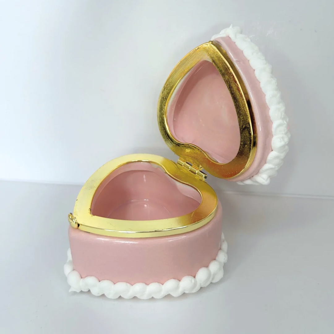 Open view of a pink kawaii mini heart-shaped jewelry box with decorative cream and cute charms, revealing storage space inside.