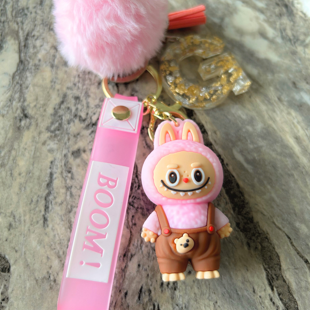 Pink Labubu doll keychain with personalized resin letter, silver flakes, and soft pink pompom and tassel.