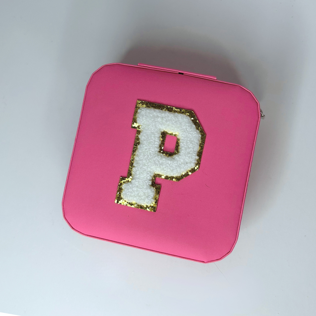 Pink square jewelry case with initial on top, closed top view.