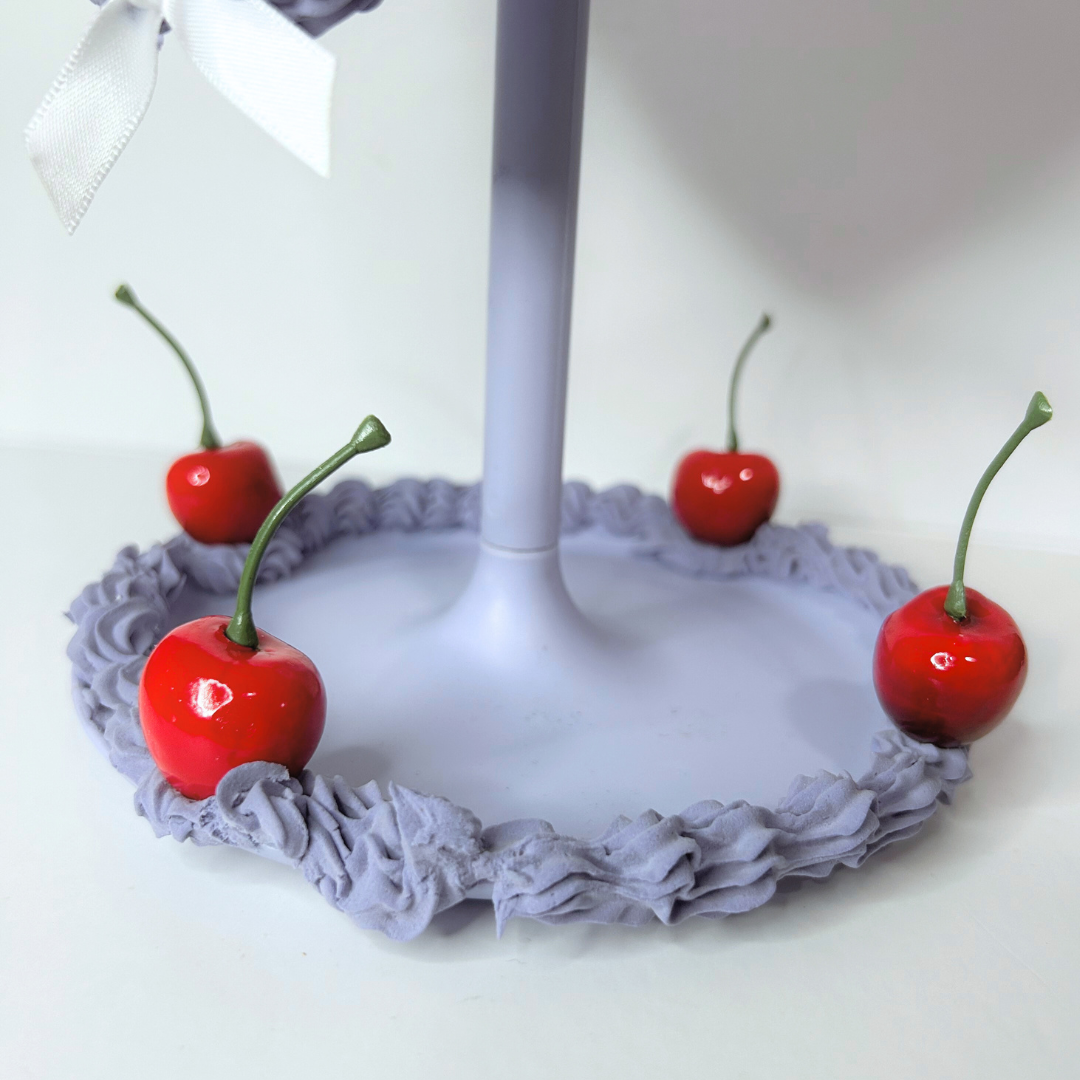 Bottom view of purple heart-shaped cake LED mirror showing built-in storage tray and cordless battery compartment.