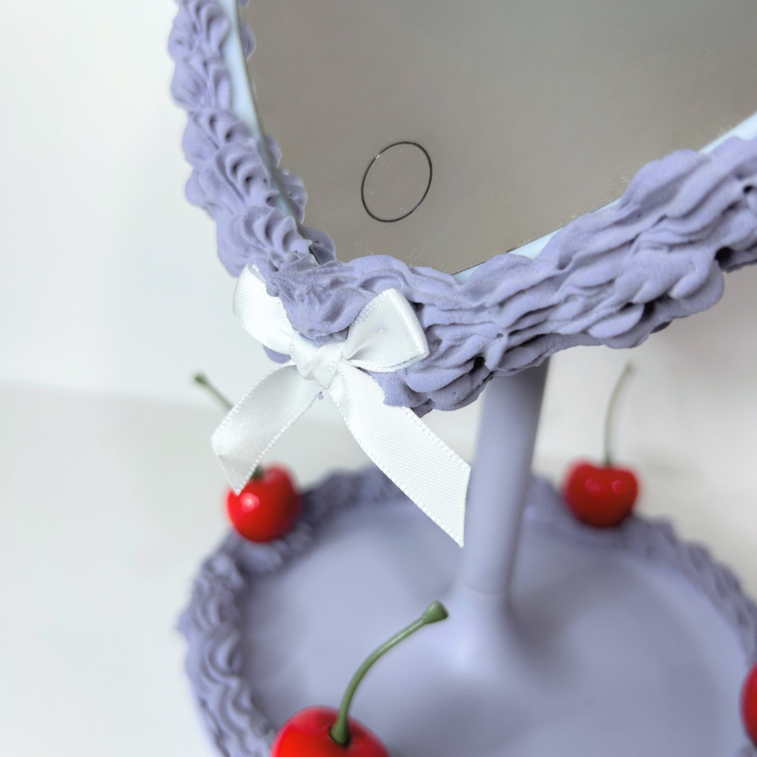Close-up of smart touch LED button on purple heart-shaped cake mirror for easy on/off lighting control.