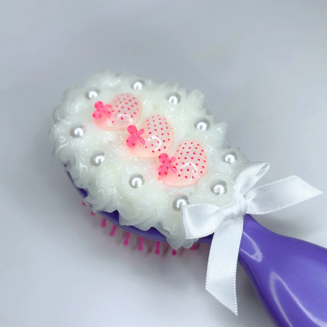Close-up of the adorable charm details on the purple travel hair brush — cute, colorful, and made to stand out