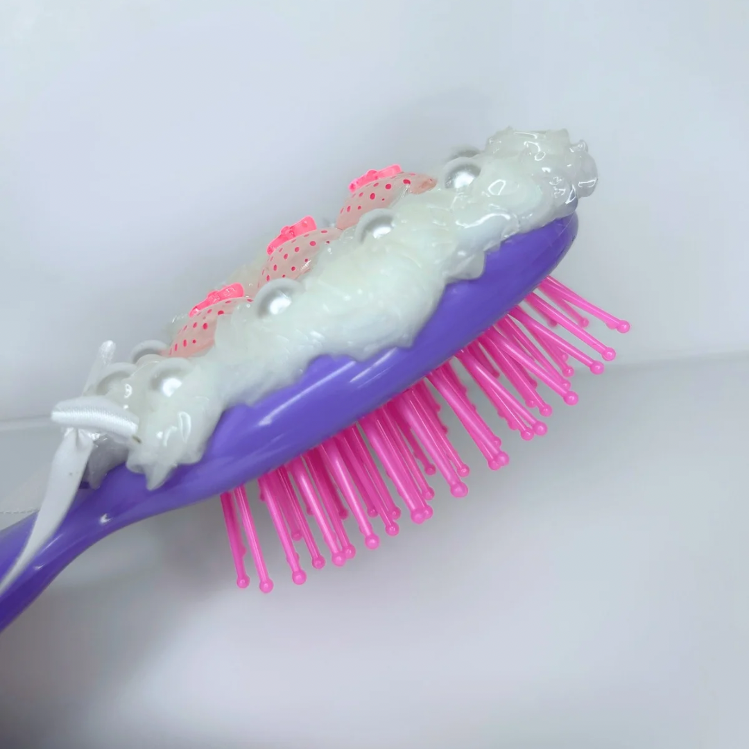 Side profile of compact purple silicon hair brush featuring pastel charms, ideal for styling while traveling.