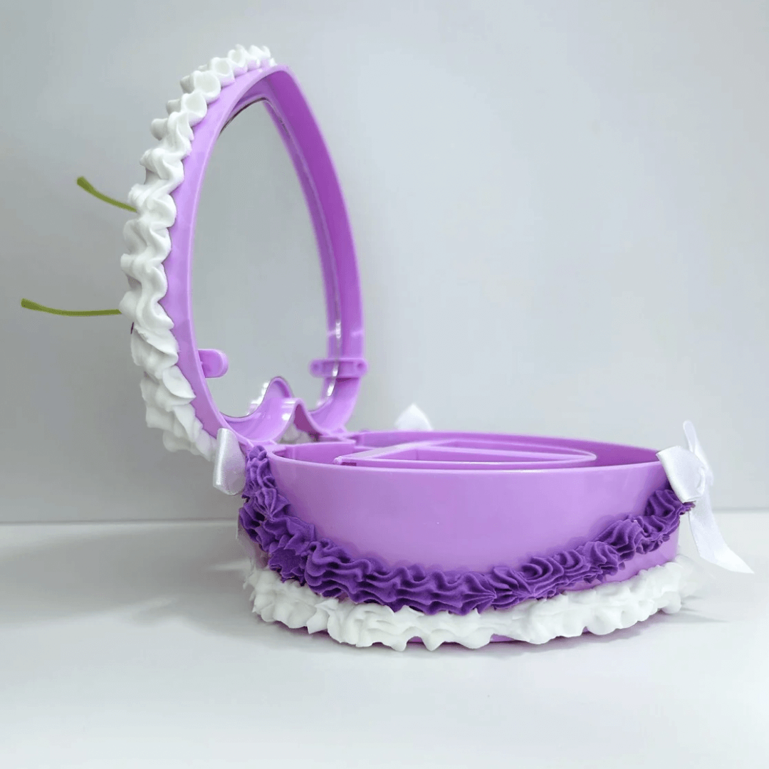 Open view of a vintage heart-shaped jewelry box revealing its spacious interior, decorated with purple and white cream, cherries, and a white bow.