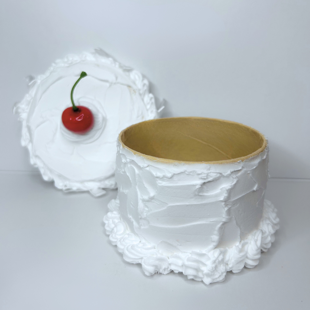 Open round cake storage box showing interior space, cherry top, and frosted white finish.