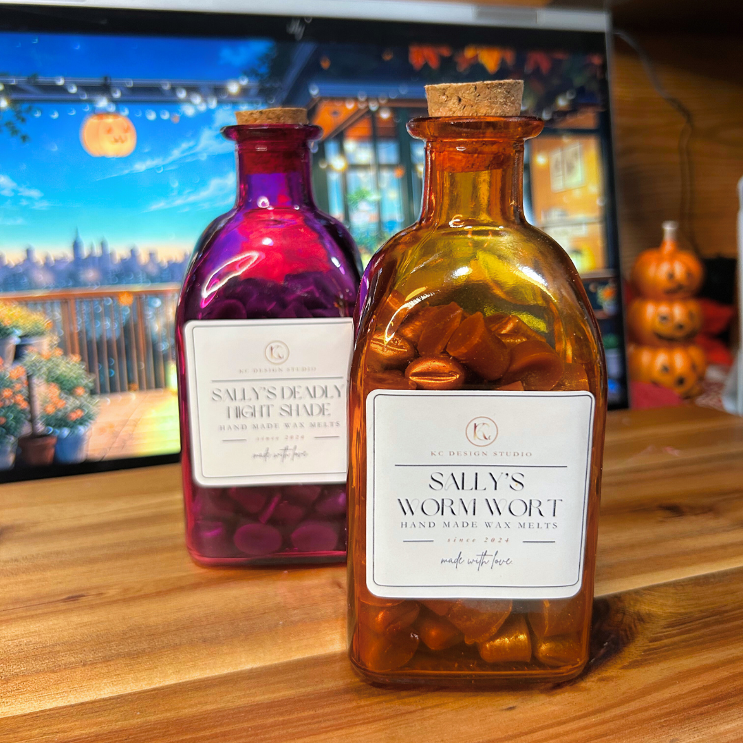 Two wax melt glass bottles with labels on a wooden surface, with a blurred background of pumpkins and a screen.
