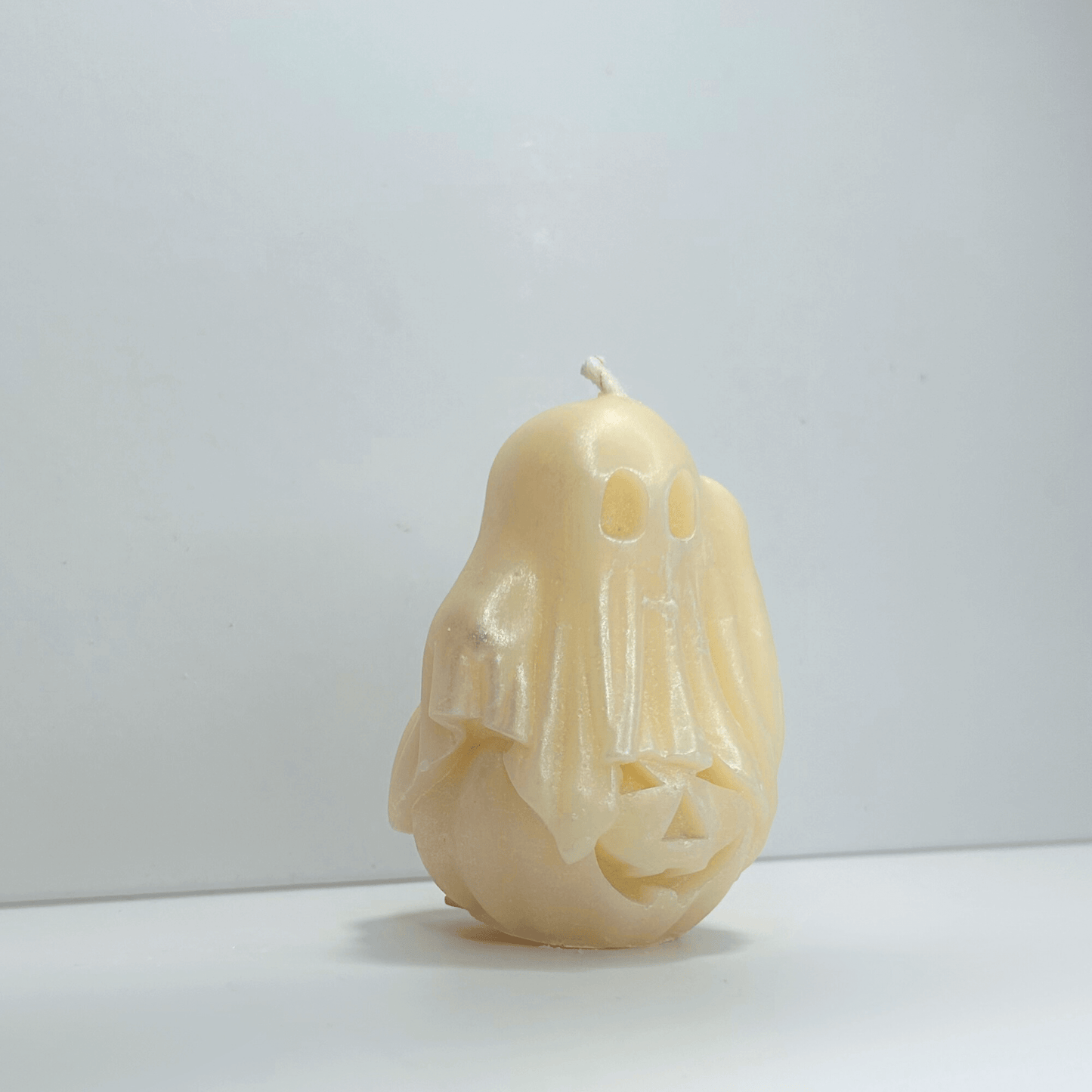 Side view of decorative ghost candle showing the detailed design of the ghost on a pumpkin, scented with cotton candy.