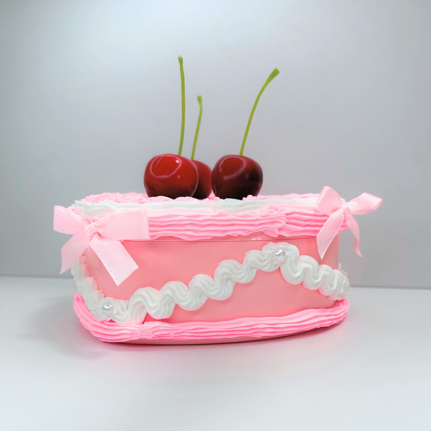 Side view of the pink and white jewelry box featuring three cherries, delicate pearls, and cute mini pink bows, highlighting its decorative details and stylish appearance.