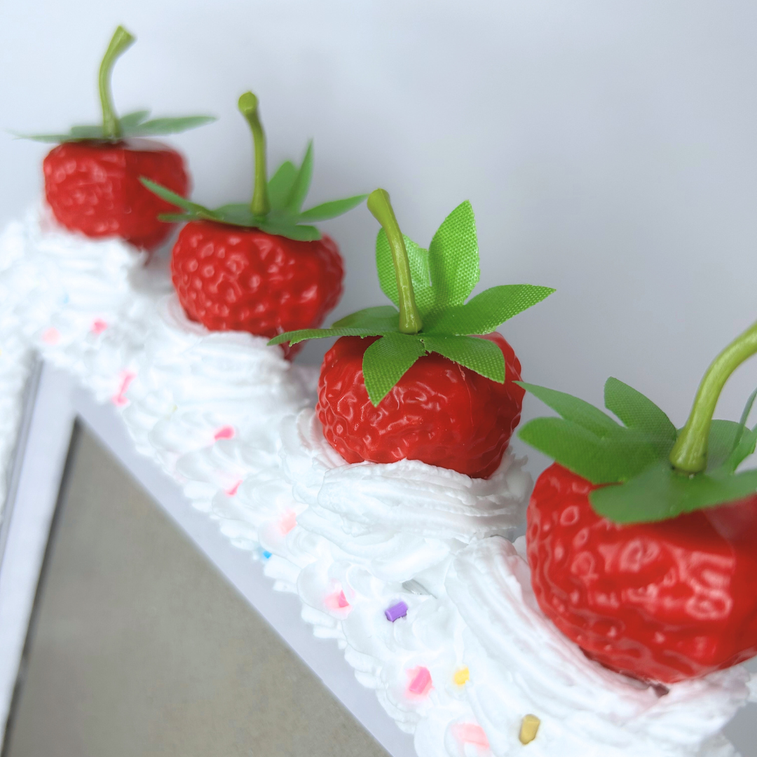 Close-up of the strawberry cake picture frame top, showcasing the four strawberries and sprinkles.