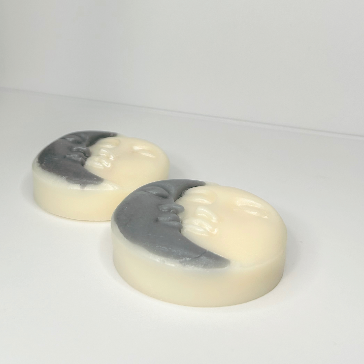Side view of two Sun & Moon wax melts highlighting their unique shapes, colors, and sleeping faces.
