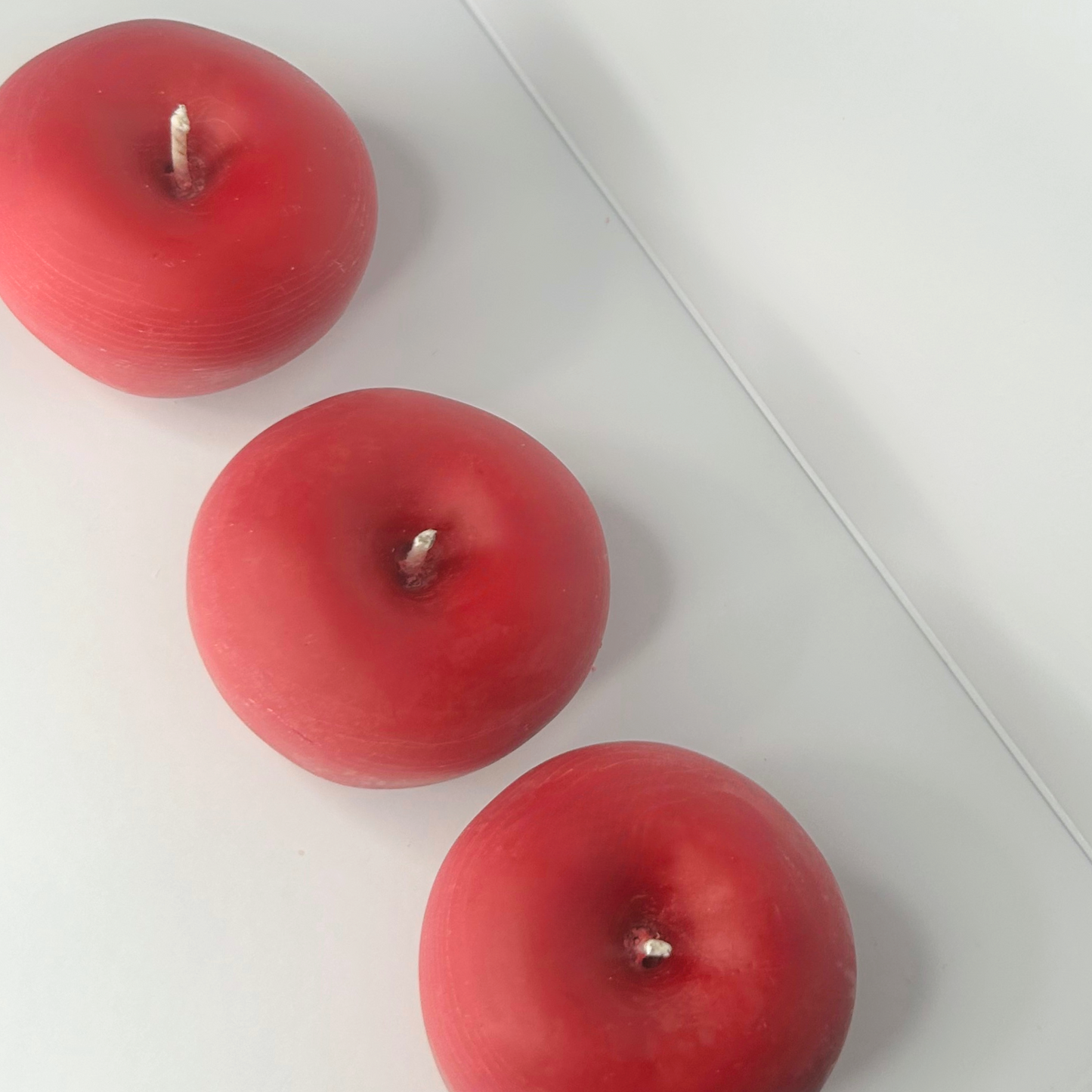 Top view of three vibrant apples lined up, showcasing their rich colors and textures, highlighting the fresh beauty of the Cranberry Apple Marmalade Candle.