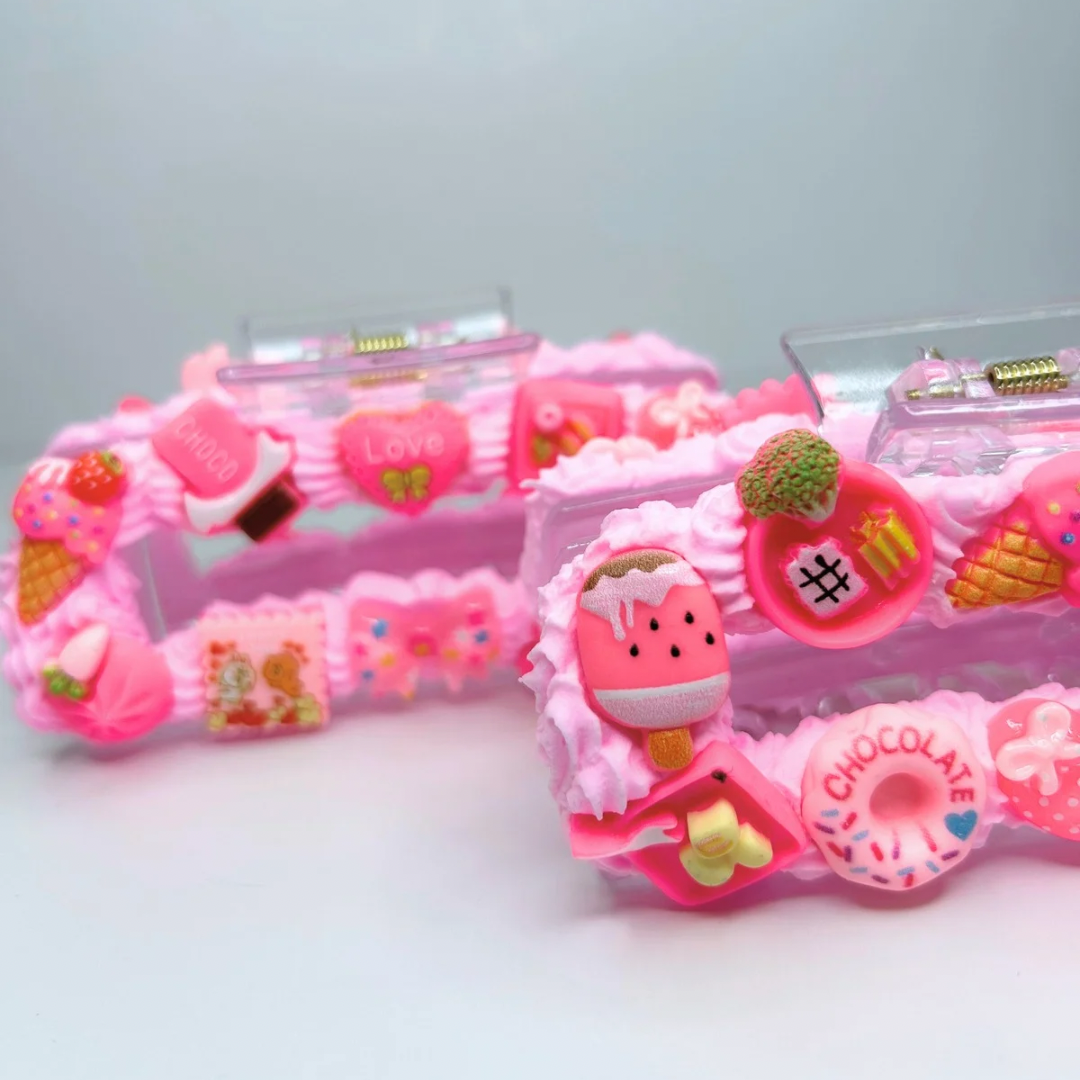 Two pink creamy hair claws with geometric design and charms - close-up view.
