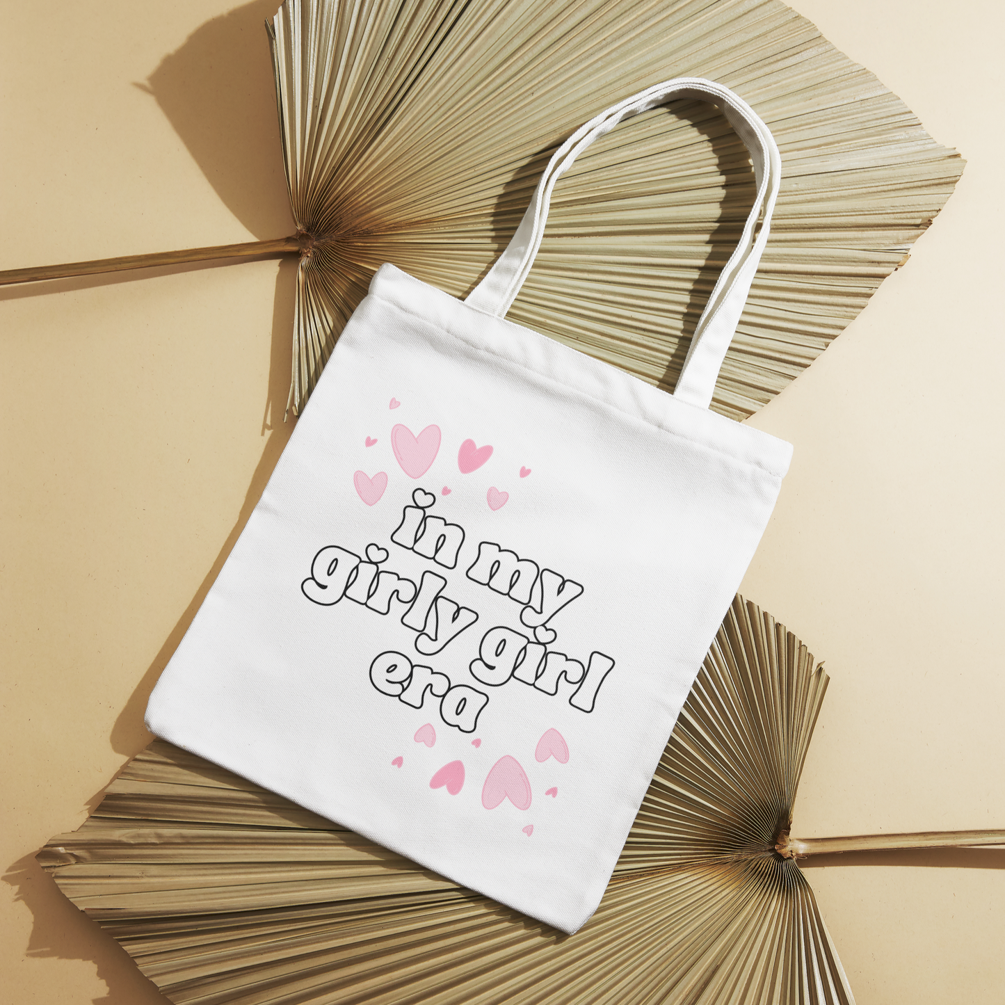 White canvas tote bag with "In My Girly Girl Era" text and pink floating hearts, perfect for daily use.