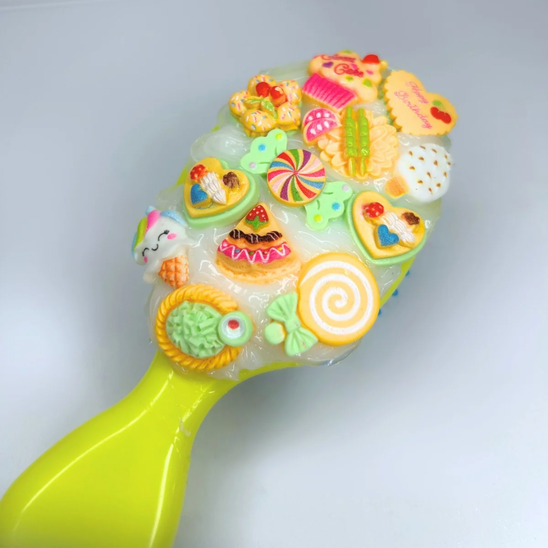 Top view of the yellow travel hair brush featuring fun, bright charm accents and flexible silicone bristles for daily styling